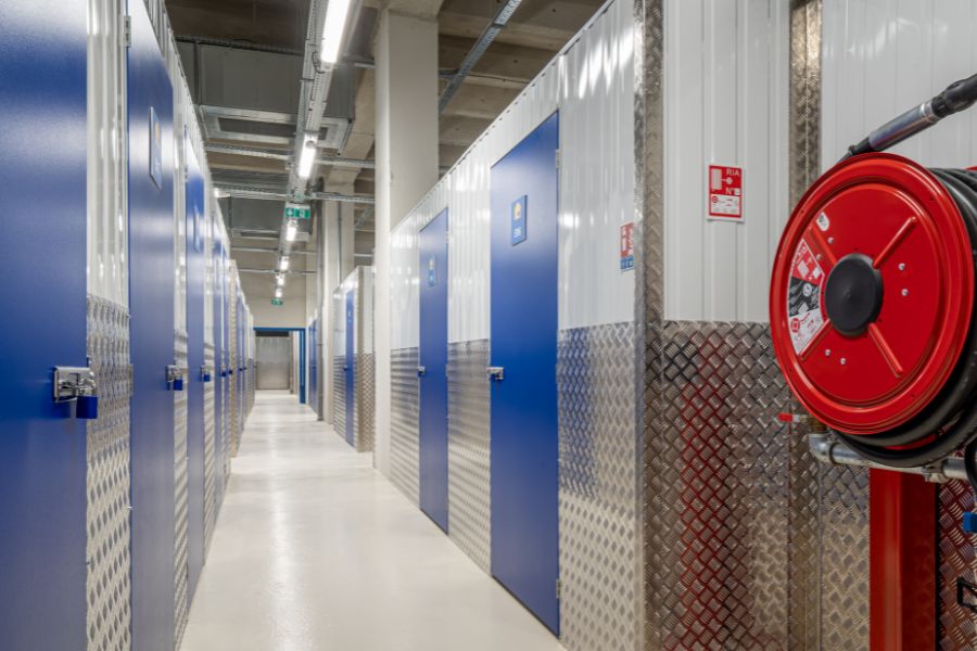 Couloir de boxes de stockage sécurisés avec portes cadenassées et dévidoir incendie dans un centre Une Pièce en Plus en Île-de-France