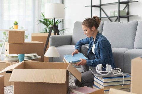 Femme assise parmi des cartons de déménagement, illustrant un besoin de stockage personnel